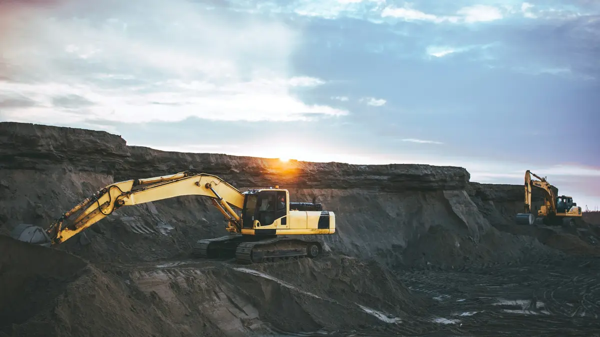 Tracked excavator working a quarry face at sunrise
